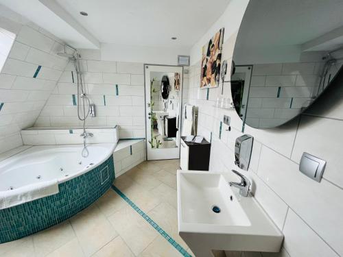 a bathroom with a tub and a sink and a mirror at Hotel Karthäuser Hof in Flörsheim