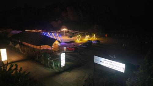 a building with cars parked in a parking lot at night at Murali Guesthouse Hampi in Hampi