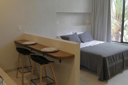 a bedroom with a bed and a table and two stools at Minimalist Verde Chapu in Guadalajara