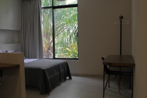 a bedroom with a bed and a desk and a window at Minimalist Verde Chapu in Guadalajara