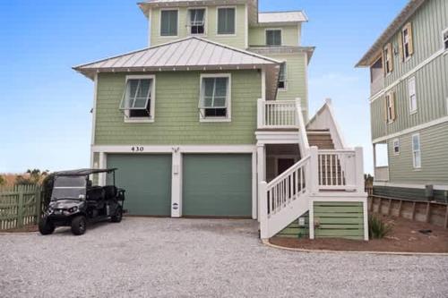 a golf cart parked in front of a green house at NEW- Gulf Front home 4 bed 4 bath in Indian Pass