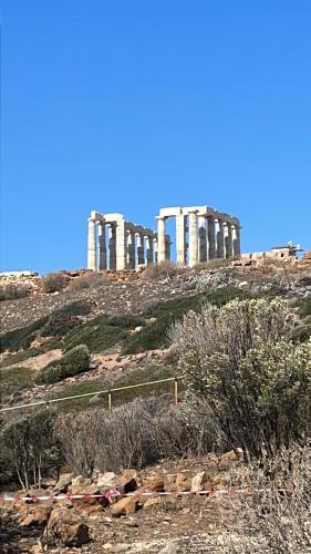 a view of a temple on a hill with bushes at Thedreamlifehouse in Anavissos