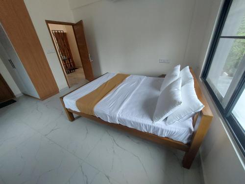 a bedroom with a bed with white sheets and pillows at Sallyies Homestay Gust House in Kottayam