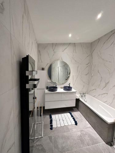 une salle de bain avec une baignoire, un lavabo et un miroir dans l'établissement L'Opale - Le Bercail, à Les Attaques