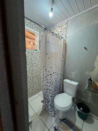 a bathroom with a toilet and a shower curtain at Chácara Leão Dourado in Pôrto Feliz