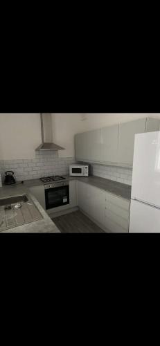 a kitchen with white cabinets and a stove top oven at Denton House in Manchester