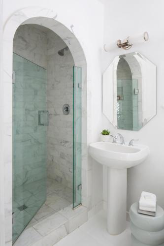a white bathroom with a sink and a shower at Avalon Hotel & Bungalows Palm Springs, a Member of Design Hotels in Palm Springs