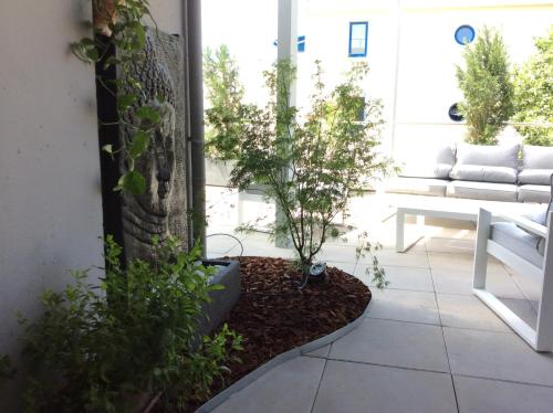 a patio with plants and a couch in the background at Les plages du Grand Vallen - Résidence Château Leenhardt in Le Grau-du-Roi