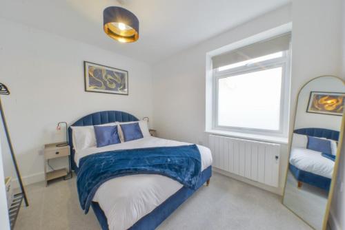ein Schlafzimmer mit einem blau-weißen Bett und einem Fenster in der Unterkunft Luxury One Bedroom Apartment St Albans By Central Stays Short Lets & Serviced Accommodation With Free Parking in St Albans