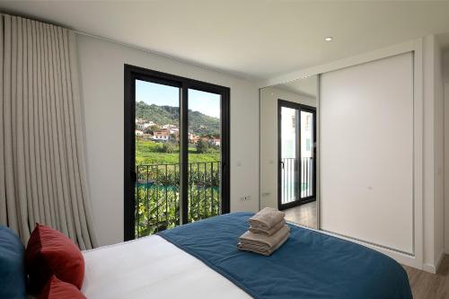 a bedroom with a bed with a view of a balcony at Marco 4 Seasons- Summer in Arco da Calheta