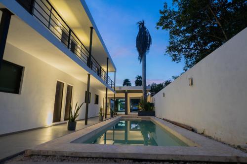 a house with a swimming pool and a palm tree at Peregrina 270 Departamentos in Motul de Felipe Carrillo Puerto