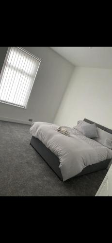 a bed in a white room with a large window at Denton House in Manchester