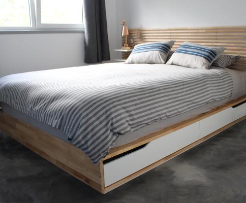 ein großes Bett mit einem Holzrahmen in einem Schlafzimmer in der Unterkunft Pukeatua Farmstay in Waimauku