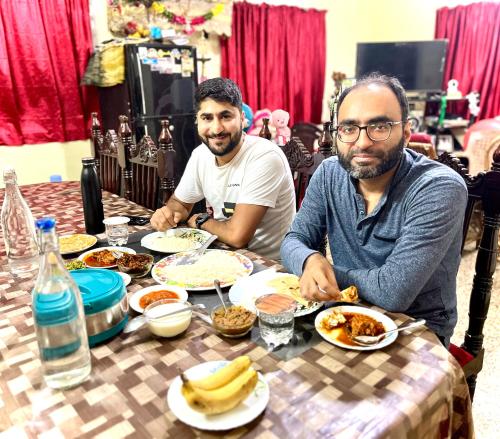 two men sitting at a table eating food at Benheal Homestay in Cochin