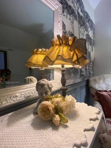 une lampe et des fleurs sur une table devant un miroir dans l'établissement La petite maison, à Solesmes