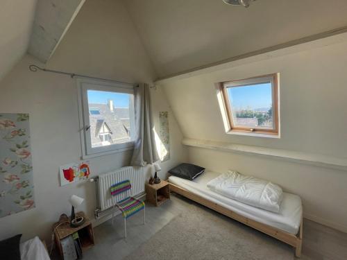a small room with a bed and two windows at Cottage with Garden 5mn Beach in Cabourg