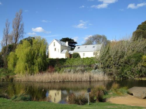 a white house on a hill next to a lake at The Mill House Cottage in Richmond