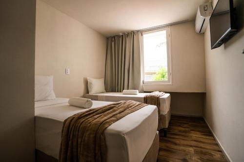 a hotel room with two beds and a window at Hotel Pipa Atlântico in Pipa