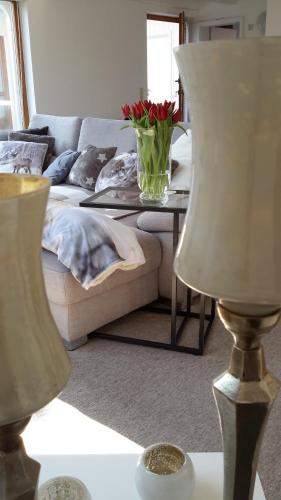 a living room with a couch and a table with a vase of flowers at Villa Clee Ferienwohnungen in Cleebronn