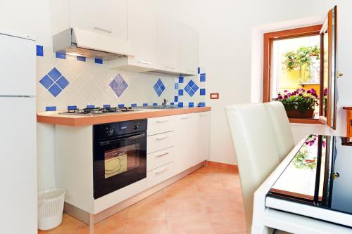 a kitchen with white cabinets and a stove at Ada's guest house in Bosa