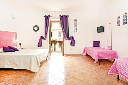 a bedroom with two beds and purple curtains at Ada's guest house in Bosa