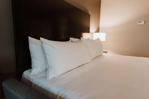 a bed with white pillows in a hotel room at Coast Nisku Inn & Conference Centre in Nisku