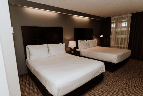 two beds in a hotel room with white pillows at Coast Nisku Inn & Conference Centre in Nisku