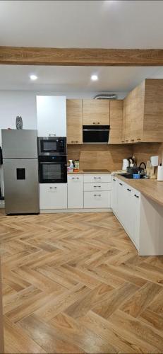a large kitchen with white cabinets and wooden floors at Casa Adam B in Gara Ilişeşti