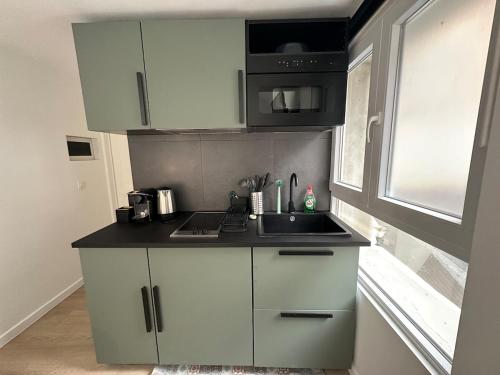 a kitchen with white cabinets and a sink and a window at Ixelles - Cozy studio in middle of European District in Brussels