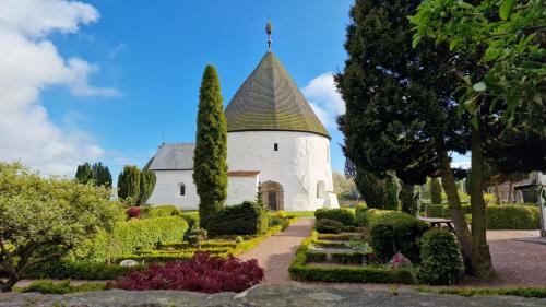 a white church with a turret in a garden at Charmerende lejlighed i den gamle kirkesmedje in Rønne