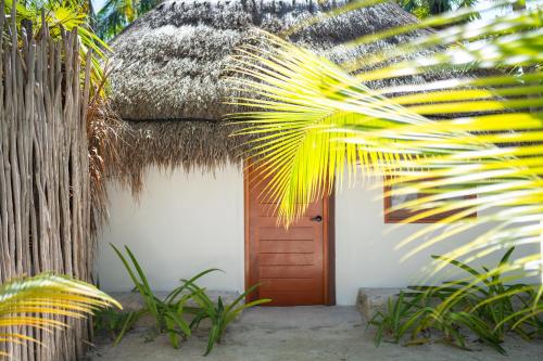 un edificio con tetto di paglia, porta e palma di Alito Tulum Hotel a Tulum