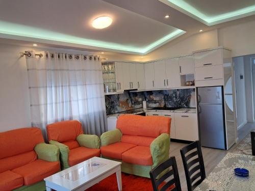 a living room with two orange chairs and a kitchen at Jurgen House in Piskupat