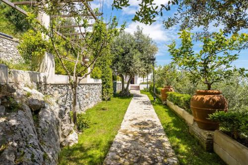 a garden with a stone wall and two large vases at Villa Antonella Amalfi Coast in Praiano