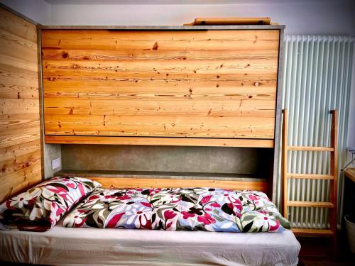 a bed in a bedroom with a wooden headboard at Fiore delle Alpi in Bellamonte