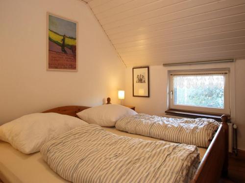 two beds in a small room with a window at Ferienwohnung im Reetdachhaus, Burhave in Burhave
