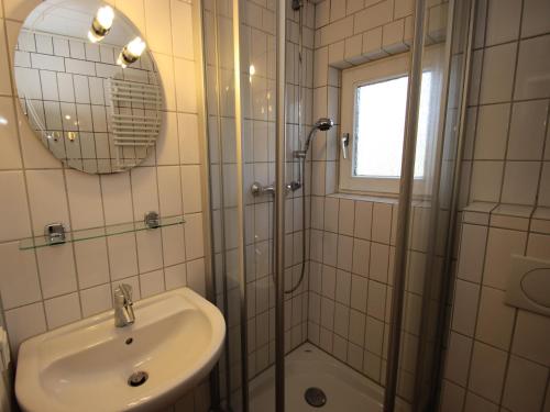 a white bathroom with a sink and a shower at Ferienwohnung im Reetdachhaus, Burhave in Burhave
