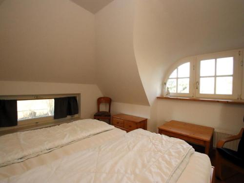 a bedroom with a white bed and two windows at Ferienwohnung im Reetdachhaus, Burhave in Burhave