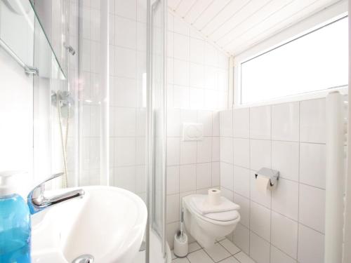 a white bathroom with a toilet and a sink at Ferienwohnung im Reetdachhaus, Burhave in Burhave