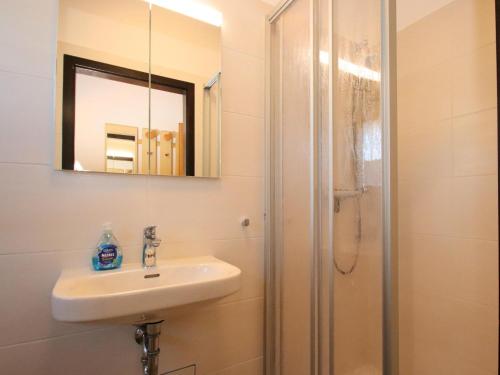 a bathroom with a sink and a shower with a mirror at Freistehender Ferienbungalow im Fachwerkstil in Burhave