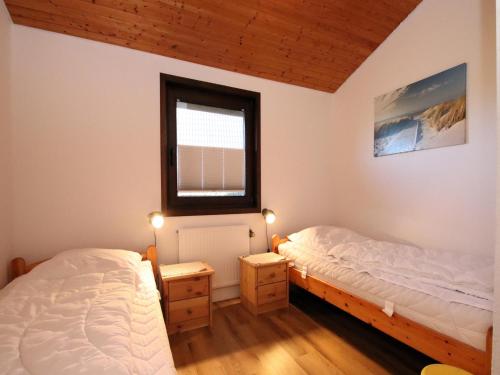 two twin beds in a room with a window at Freistehender Ferienbungalow im Fachwerkstil in Burhave