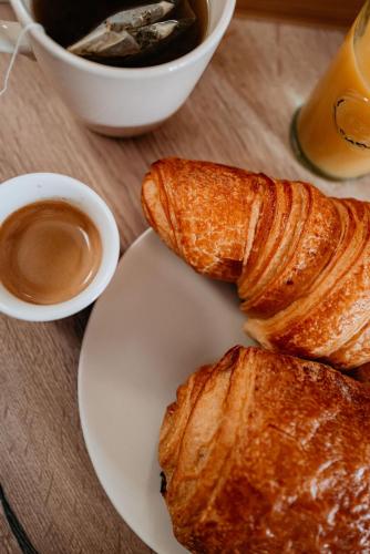 a white plate with croissants and a cup of coffee at Le Chat Léon in Chalon-sur-Saône