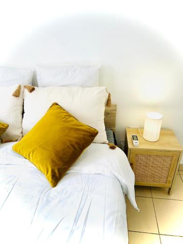 a white bed with a yellow pillow on it at T2 ILONA - neuf, 8min airport in Saint-Denis