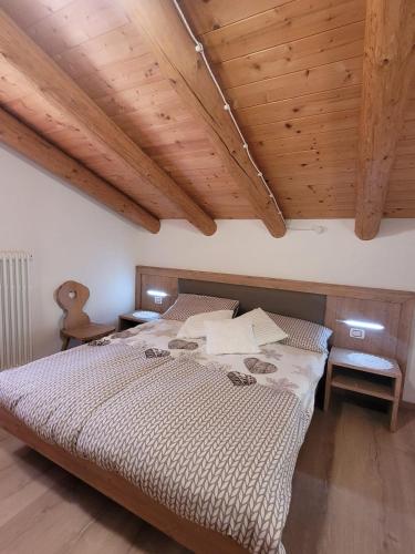 a bedroom with a large bed with wooden ceilings at Baita il nido dell'aquila in Fierozzo