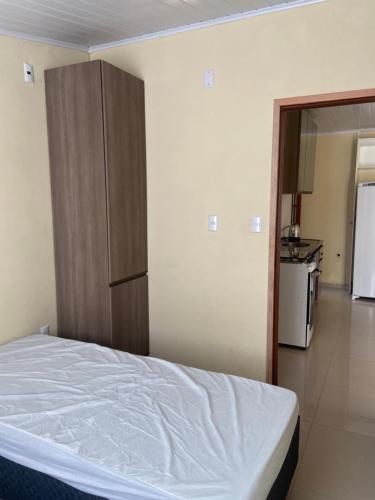 a bedroom with a bed and a cabinet and a kitchen at Recanto do Sol Praia do Cassino in Rio Grande
