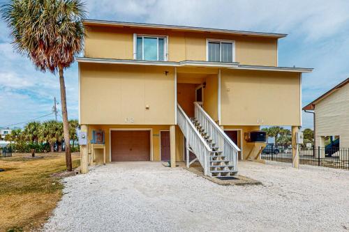 a yellow house with a staircase in front of it at Pensacola Beach Condos in Pensacola Beach