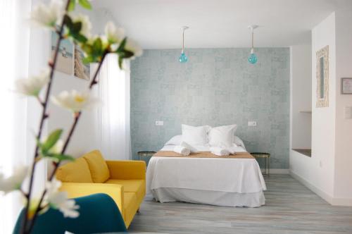 a bedroom with a bed and a yellow couch at Olivia Apartments TRG in Benidorm