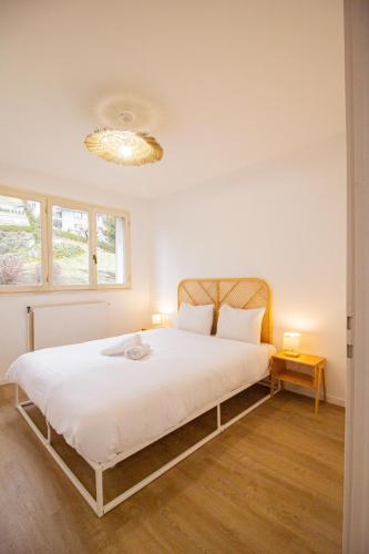 une chambre avec un grand lit blanc avec un lustre dans l'établissement Le Mirat - Private & Balcon, à Albertville