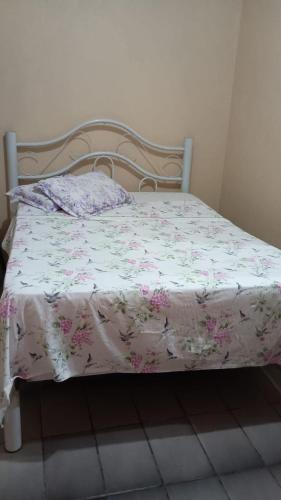 a bed with a white blanket with flowers on it at Casa albatroz Imbé in Imbé