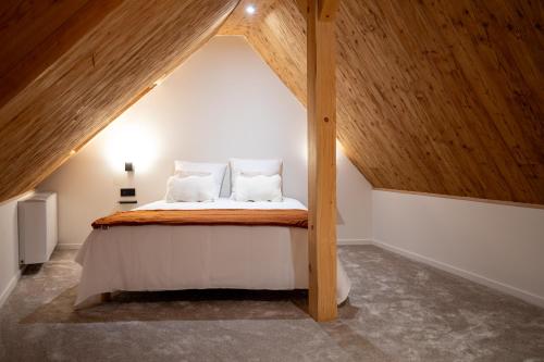 a bed in a attic with a wooden ceiling at Haut Koeur du Château in Saint-Hippolyte