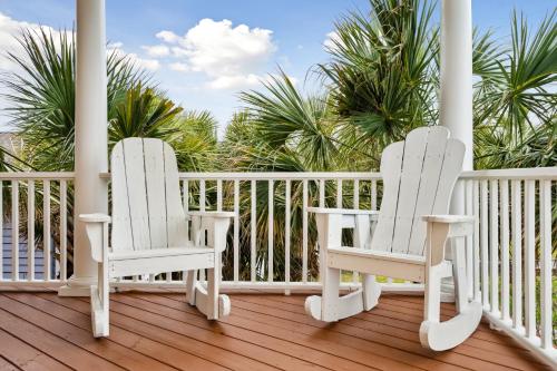 two white chairs sitting on a porch with palm trees at Oceanfront w Pool Panoramic Deck Views 5BDR Folly Ocean Breeze by AvantStay in Folly Beach